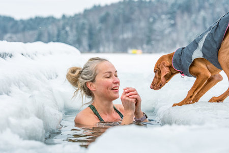 Vilnius, Lithuania - February 8 2026: Beautiful blonde hair woman immersed in the freezing cold water of a lake practicing cold water swimming. Wim Hof Method, cold therapy, breathのeditorial素材