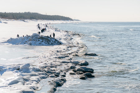 Icy winter seascape with frozen waves, floating ice floes on the sea water along a snowy shoreline...