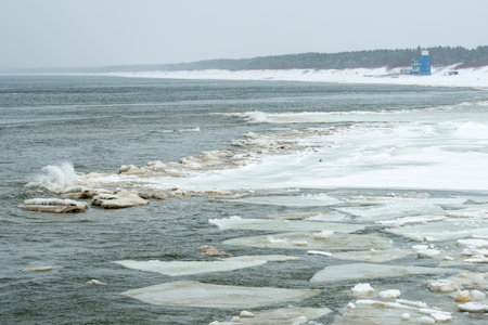 Icy winter seascape with frozen waves, floating ice floes on the sea water along a snowy shoreline on the Baltic Sea in Palanga, Lithuaniaの写真素材
