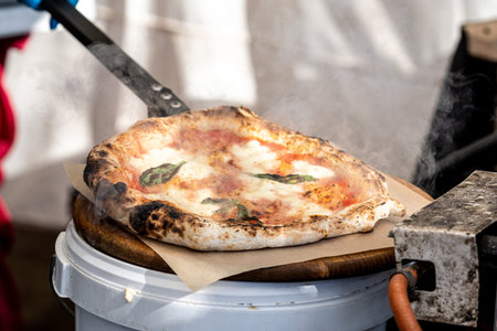 Pizza Margherita with tomato sauce, fresh mozzarella cheese and basil leaves on a wooden board with smokeの写真素材