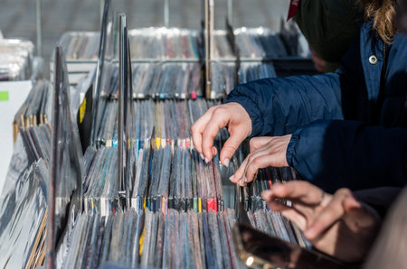 People browsing vinyl records in crates at a flea market. Close-up of hands flipping through vintage LP albumsの写真素材