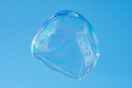 Floating soap bubble reflecting a city and the architecture against a clear blue sky, creating a...