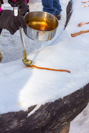 Pouring maple syrup on snow making maple taffy during sugar shack periodの写真素材