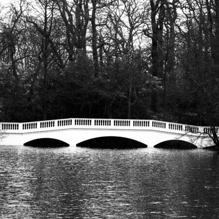 Black and white picture who depicts a wooden white garden bridge who spans a lake.の写真素材