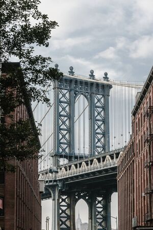 Manhattan bridge seen from a narrow alley enclosed by two brick buildings on a sunny day in summerの写真素材