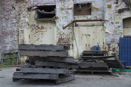 Exterior ruins of an abandoned warehouse with brick paint peeling walls, wooden and plastic crates,...