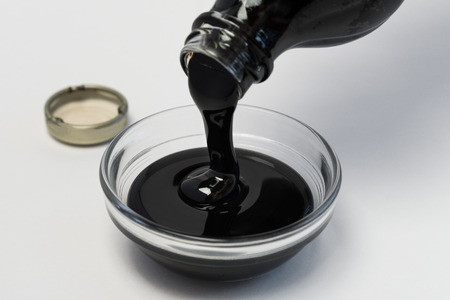 Pouring molasses into an ingredient bowlの写真素材