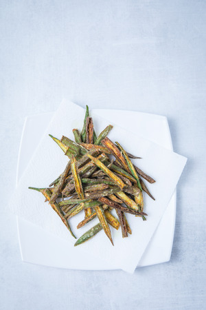 Deep fried okra on white square plates and a white background. Fried bhindi with Indina spices. Green fried okra.の写真素材