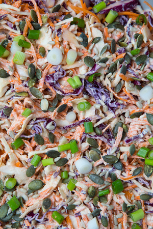 Close view of raw grated vegetables with mayonnaise, chives and pumpkin seeds. Colourful salad.の写真素材