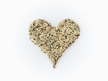 Shelled hemp seeds shaped in a heart symbol isolated on whiteの写真素材