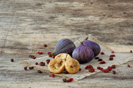 Fresh and dried figs with berries and raisins on woodの写真素材