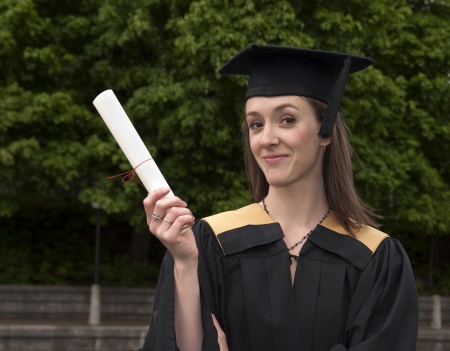 Young woman shows off certificate on graduation day の写真素材