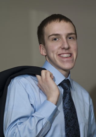 Young business man with braces standing holding suit coat over shoulder の写真素材