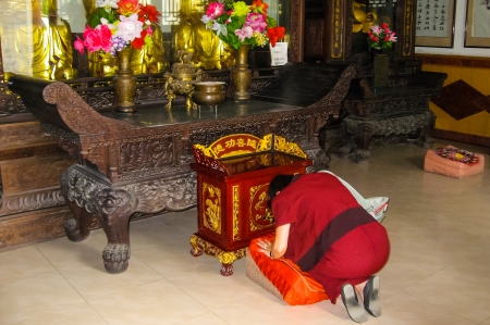 Woman praying in front of a traditional Buddha statueのeditorial素材