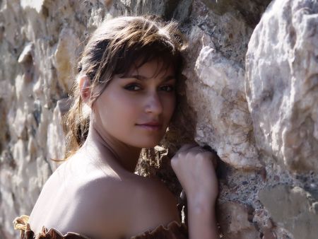 Glamour young woman leaning to stone wallの写真素材