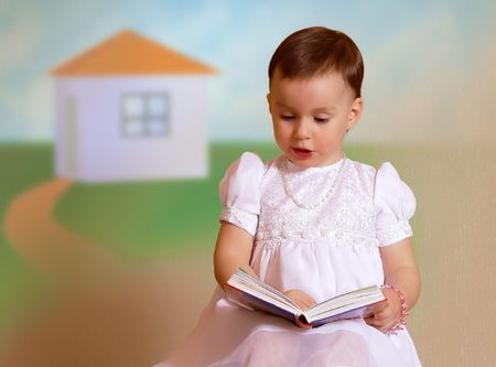                    Little girl in a white dress dreams about a book            の写真素材