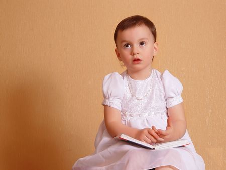 Little girl in a white dress dreams about a bookの写真素材