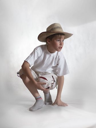 Sitting boy in straw hat on gray background looking rightの写真素材