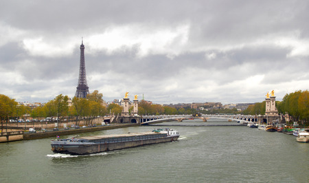 Eiffel Tower on the bank of river Seine with ship at cold spring cloudy dayの写真素材