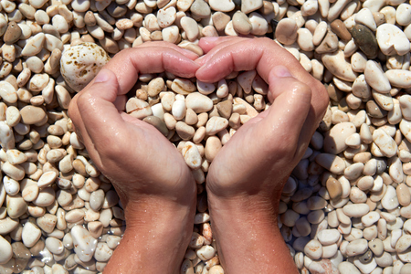 Hands in the form of heart with pebbles insideの写真素材