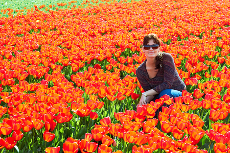Portrait  happy brunette woman in flowers of red tulips fieldの写真素材