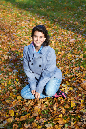 happy young teen girl in autumn scenery throwing leavesの写真素材