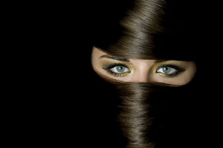 Beautiful girl with lovely eyes covered by burka made of her own hairの写真素材
