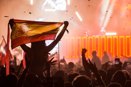 Girl at a festival with a Spanish flag on the shoulders overlooking the crowdの写真素材