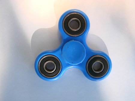 Blue fidget spinner stress relieving toy on white backgroundの写真素材