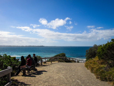 Point Nepean, AU - 2 Mar 2015: National park coastal view with a group of Asian tourists in sight. They are sitting on wooden bench at the designated lookout pointのeditorial素材