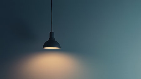 Single black hanging lamp with light on a dark moody background. modern industrial designの素材