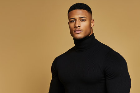 Fit man in black turtleneck posing confidently against mustard yellow background. strength and sophisticationの素材