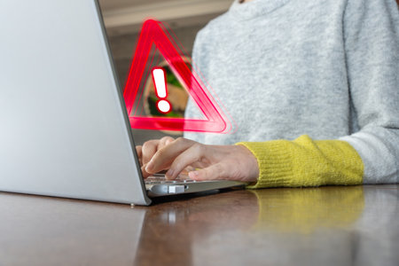 Hands typing on laptop with cybersecurity warning symbol, concept of online security and data...