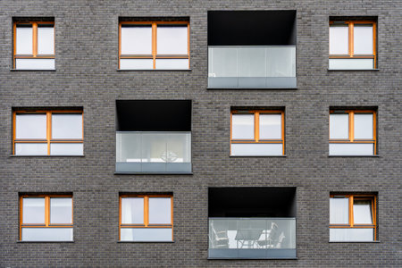 Modern apartment building facade with symmetrical windows and glass balconies, urban housing architectureの写真素材
