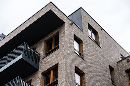 Corner of urban apartment building with overhanging roof and metal balcony, minimal architectureの写真素材