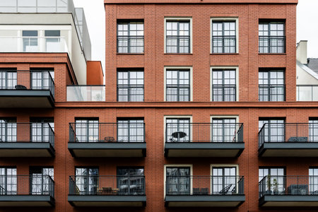 Red brick residential apartment building with black rail balconies, modern urban housing