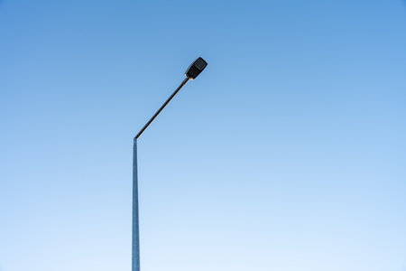 Minimalist image of a single street lamp against clear blue sky, capturing urban infrastructure and clean design in modern environmentの写真素材