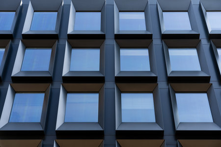 Frontal view of sleek contemporary building with deep square windows creating rhythmic architectural...