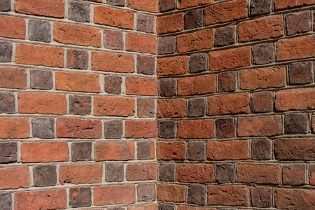 Detailed corner view of an old red and black brick wall texture with defined mortar joints under daylightの写真素材