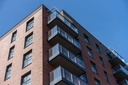 Modern brick apartment building with glass balconies, contemporary residential architecture in...
