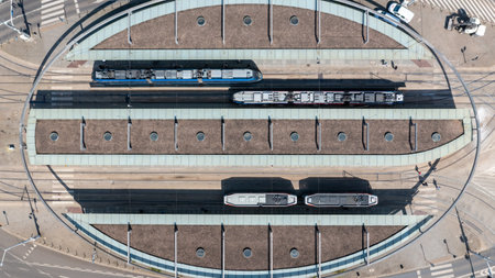 Top-down aerial shot of modern tram station with multiple trams and platform roofs, highlighting organized urban public transportation systemの写真素材