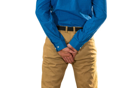 Male adult with both hands shielding buttocks area, suggesting discomfort or protection in health or social situationsの写真素材