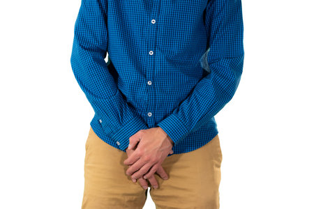 Man covering groin area with hands in protective manner suggesting discomfort, pain or reaction to sensitive situation. Isolatedの写真素材