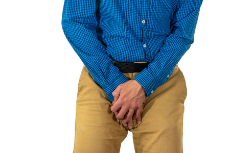 Man in casual attire shielding groin area with hands while standing in defensive position suggesting...