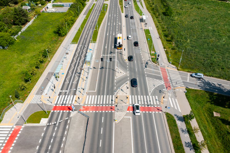 Major multilane road intersection with public bus stop and crosswalks in suburban area with cars in...