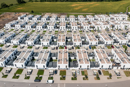 Top-down aerial view of suburban housing grid with identical two-story white homes and lawnsの写真素材