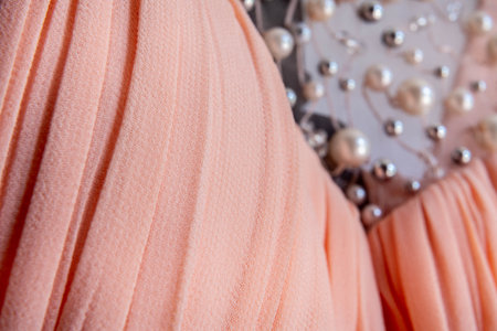 Close-up of soft pleated peach textile with decorative pearls and beaded detail for luxury fashion and design backgroundの写真素材