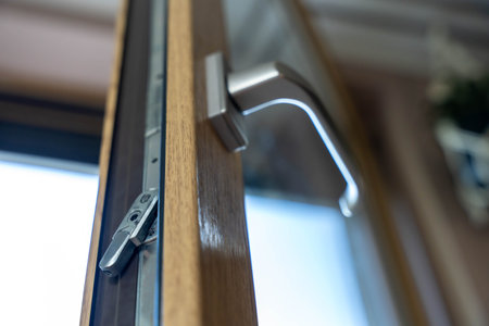 Modern window handle with lock mechanism on wooden frame, interior low angle view of residential opening systemの写真素材