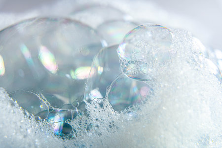 Shiny transparent soap bubbles in foam cluster, macro detail of colorful cleaning surface conceptの写真素材
