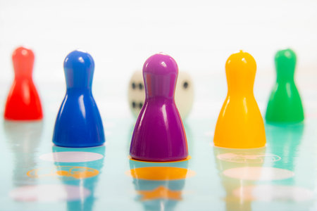 Colorful plastic pawns in a row on game board depicting teamwork and playful competitionの写真素材